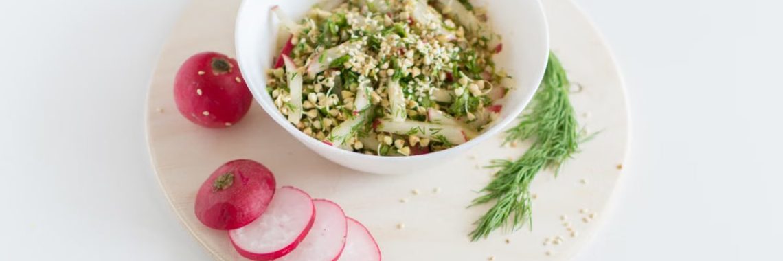 A healthy vegan salad with buckwheat, radish, and dill garnished with sesame seeds.